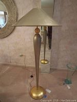 Front view of slender floor lamp with gold leaf shade and base, silver baluster shaft