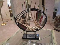 Full frontal view of the abstract polychrome and gilt sculpture on rectangular black plinth base.