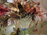 Clear crystal centerpiece bowl with fluted design filled with silk flowers on glass table