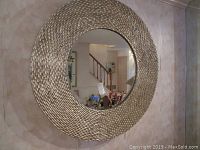 Full view of round mirror mounted on wall showing textured silver frame and beveled glass.