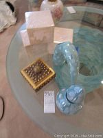 Modernist glazed pottery cubes and vessels alongside a Roma gilt box on glass table