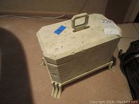 Front and side view of the stone textured plaster box on metal stand with handle on lid and claw feet on stand.