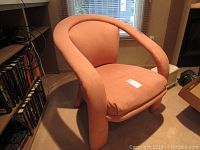Front and angled view of oversized dusty rose arm chair showing rounded curves and thick cushion.
