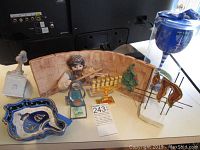 Group photo of the pottery menorah with a fiddler figurine, a decorative blue ceramic dish, gold menorah, abstract animal figurines, and blue glass goblet