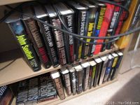 Shelf showing a row of CD cases mainly featuring John Sanford titles along with other subjects.