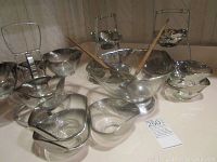 The set arranged on a surface showing all glass bowls with silver tint held in chrome stands and wooden utensils.