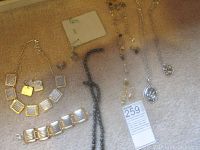Full view of multiple Brighton and other jewelry pieces laid out on light carpet including necklaces, bracelet, earrings.