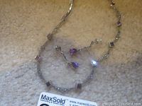 Photo showing the sterling silver necklace and matching dangling earrings featuring marcasite, amethyst, and spinel purple stones, lying on a fabric surface.