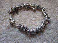 Coiled view of entire bracelet showing silver charms and barrel clasp