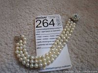 Three-strand pearl bracelet laid flat with box clasp visible