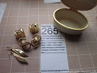 Overview of three pairs of earrings and open Lenox porcelain box on grid