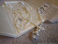 Pearl necklace displayed on satin-lined jewelry folder showing graduated pearls and decorative clasp