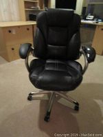 Full front view of black office chair with padded backrest, seat, armrests, and chrome base with caster wheels.
