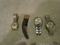 Four men's wristwatches laying flat showing bands and faces, including Seiko, Fossil and Timex, gold and silver tone bands, untested.