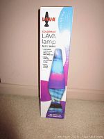 Full view of the original packaging box of a Colormax lava lamp highlighting its height, hand-painted tri-colored globe, Northern Lights Look decals on base and cap, and multi-color effect.