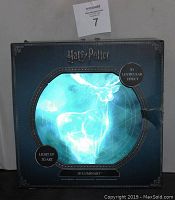 Front of the unopened box featuring Harry Potter logo, image of a glowing stag in 3D light-up art with lenticular effect