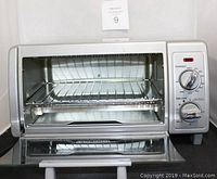 Front view of Black & Decker toaster oven showing inside with wire rack and control dials on the right.