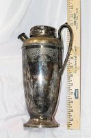 Full front view of the engraved silver plated decanter beside a ruler showing approx. 13 inches tall.