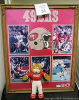 Full view of the framed 49ers memorabilia with central helmet graphic and five football action photos on red background with ornate wood and glass frame