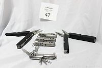 Photo showing six utility multi tools with black handles and stainless steel blades and tools, including pliers, knives, and corkscrews, arranged on white background.