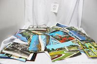 Photo showing a pile of vintage postcards with various photographic images, some colored and some black and white.