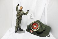 G.I. Joe action figure standing on a display stand next to green USMC hat with emblem and Grim Reaper pin