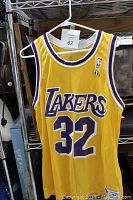 Full front view of yellow Lakers Magic Johnson #32 jersey on hanger showing cloth texture and color.
