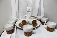 Front view of the set showing cups, creamer, sugar bowl with lid on a white surface