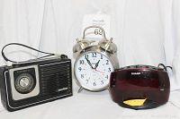 All three items together: Meriton radio on left, Sharp quartz alarm clock in center, Sharp digital clock on right