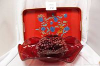 Lot of items including ruby red depression glass bowl, clear square candy dish, grape clusters, and red lacquer serving tray with floral pattern behind