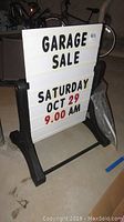 Front view of the garage sale sign on black stand with letters forming event details.