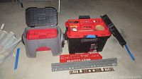 Two Craftsman tool boxes including black with red top and grey with black top, along with metal brackets laid in front
