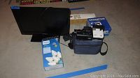 Insignia flat screen TV, Phillips warm white lights in box, JVC handheld video camera, Olympus D580 camera in box, Vivitar 901 tripod box visible.