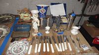 Overview of flatware including forks, knives, ceramic figures, and various vases and plates on a table