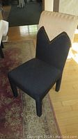 Front view of single black fabric dining chair with gold decorative top and stud accent trim.