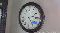 Decorative round wall clock with Roman numerals in a vintage-style frame, approximately 18 inches in diameter.