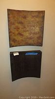 Two geometric carved wall art panels mounted on wall, lower pieces shown, one with Norwalk Furniture sticker on backing.