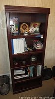 Full view of Sauder wooden bookcase with contents.