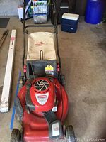 Front and top view of red Craftsman Gold engine mower with fabric grass catcher bag and handle in garage setting.