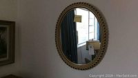 Oval wall mirror on wall, carved frame with circular accents