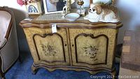 Front view of wooden cabinet with floral painted doors, showing overall condition and design.