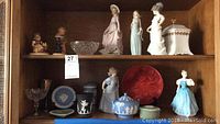 Two shelves showing porcelain figurines and jasperware pieces