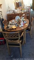 Full view of wooden dining table with items on top and four matching chairs around it.
