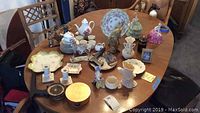 Table with entire collection showing porcelain pieces including figurine, tea set, dishes, vases, candlesticks, and coasters