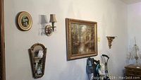 Photo showing the overall wall display including the framed painting, oval wall art, mirror, wall shelf, and two wall sconces