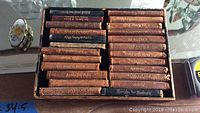 Top view of the set of 24 miniature leather-bound Shakespeare books arranged in a box, showing titles on spines