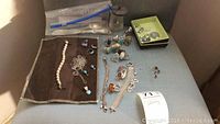 Overview of lot on velvet mat showing rings, chain, earrings tray, bracelets, knives, spoons, jar