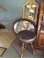 Two wood framed wall mirrors and vintage adjustable stool with claw feet visible together