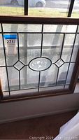 Full view of the leaded glass window panel showing central floral motif and geometric lead caming design.
