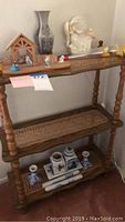 Full view of wooden shelf with multiple home décor items displayed on all tiers, including nativity scene, angel figurines, ceramic pieces, and a metal vase.